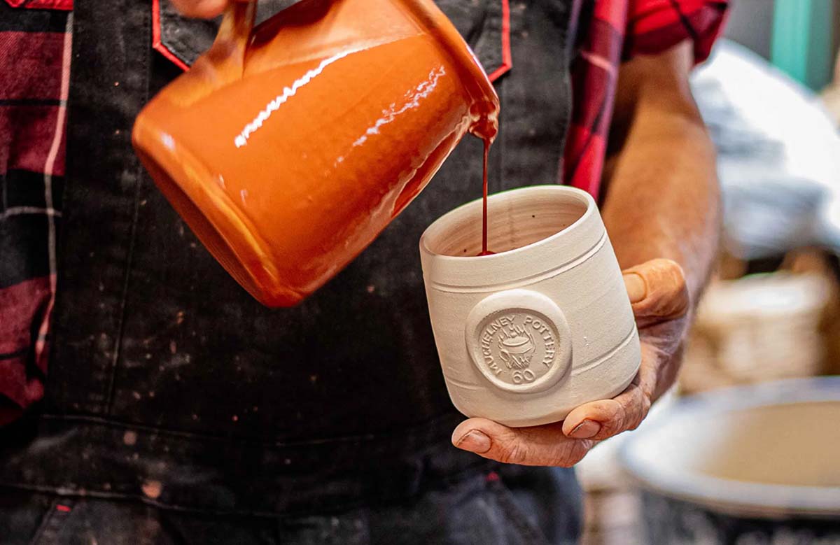 A potter glazing pots at Muchelney Pottery