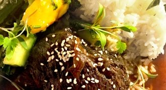 Braised beef topped with sesame seeds, served with white rice, sautéed green vegetables, and slices of yellow pepper, garnished with fresh herbs on a white plate.